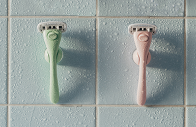 Tv&aring; rakhyvlar fr&aring;n estrid som h&auml;nger p&aring; en kakelv&auml;gg med hj&auml;lp av deras duschh&aring;llare.
