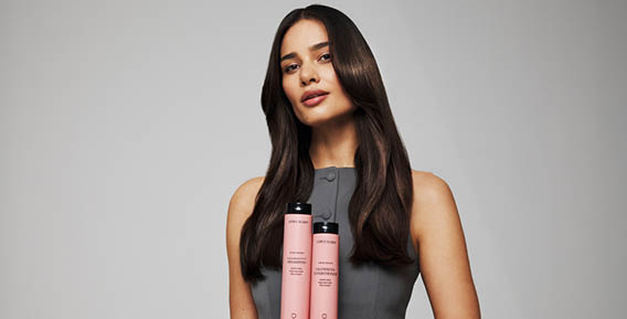 	En kvinna med l&aring;ngt brunt h&aring;r h&aring;ller tv&aring; h&aring;rprodukter fr&aring;n L&ouml;wengrip i handen.