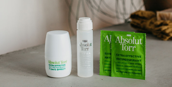 Roll- on, dab-on och servetter fr&aring;n Absolut Torr placerade bredvid varandra mot en gr&aring; b&auml;nkskiva med en handduk i bakgrunden.