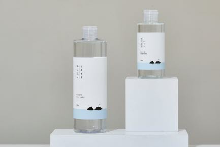 Tv&aring; RoundLab hudv&aring;rdsflaskor st&aring;r p&aring; vita block framf&ouml;r en neutral bakgrund. Flaskorna har minimalistiska etiketter med bergsikoner och en ljusbl&aring; f&auml;rgdetalj.