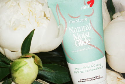 FemCare Natural Moist Glide fr&aring;n RFSU liggande bland vita pioner och gr&ouml;na blad.