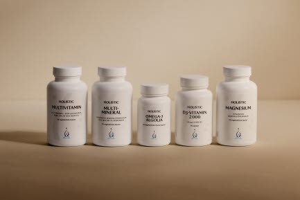 Fem flaskor med Holistic kosttillskott (Multivitamin, Multi-Mineral, Omega-3 Algeolja, D3-Vitamin 2000 och Magnesium) med vita etiketter, alla f&ouml;rpackade i vita plastflaskor. Flaskorna &auml;r arrangerade p&aring; en beige yta.
